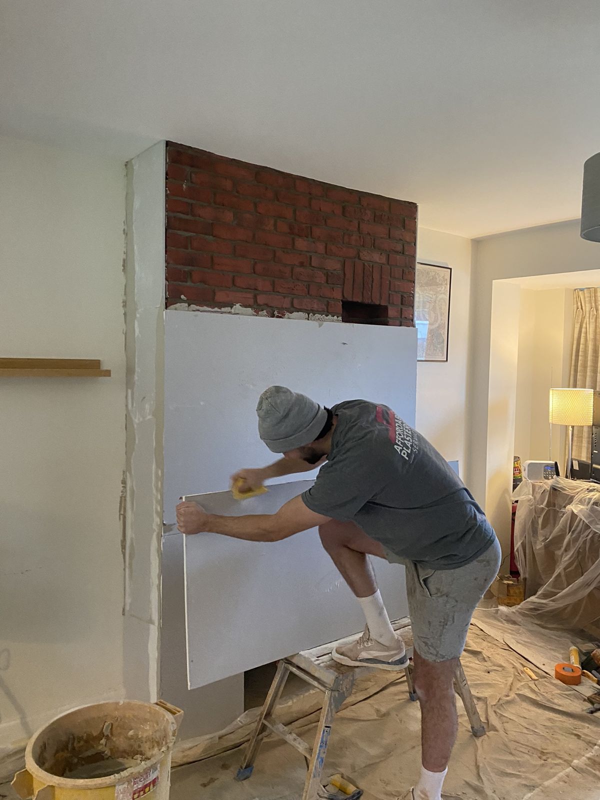 Plasterer boarding a chimney breast in a living room