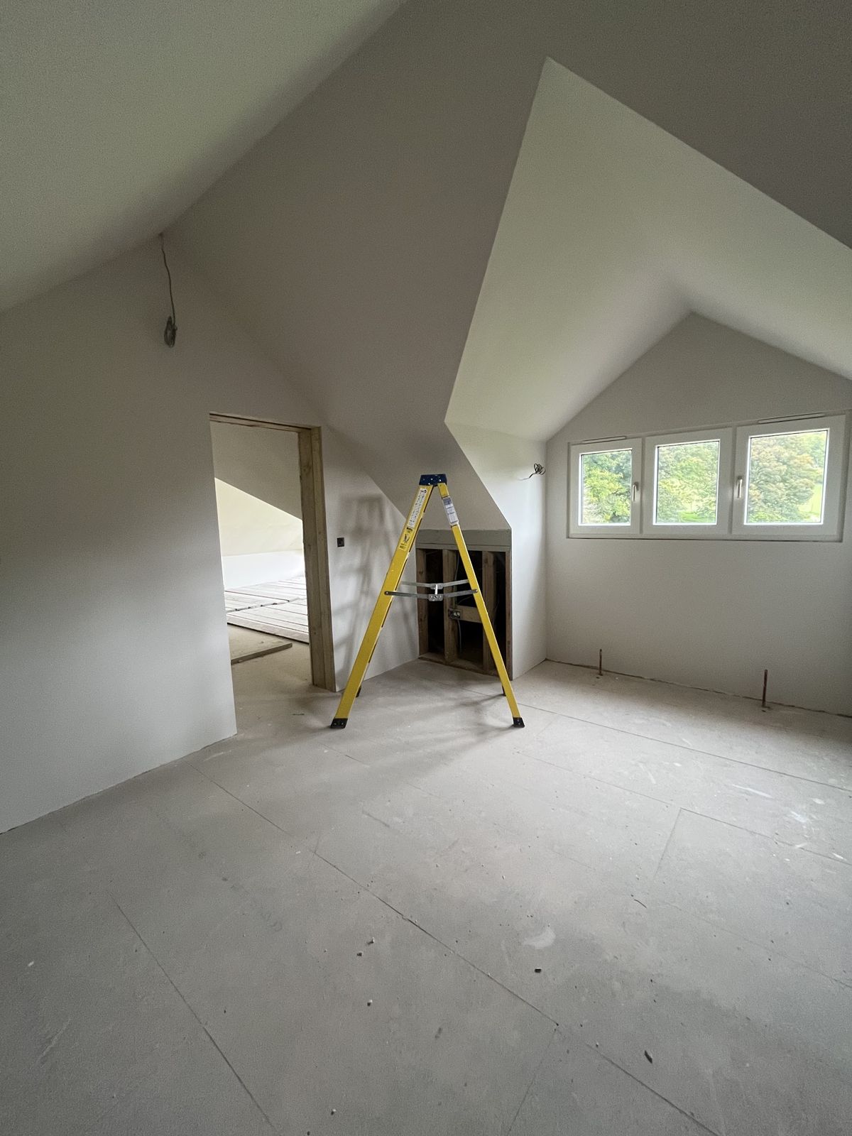 Finished loft room with a dormer window and smooth plastered walls