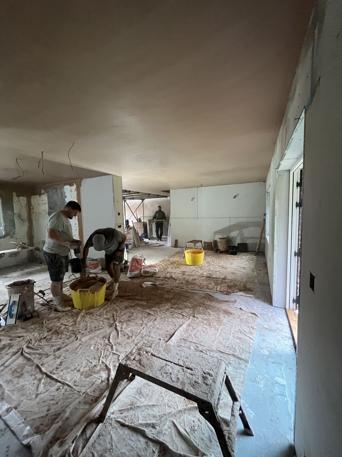 The team mixing and plastering in a large open-plan renovation